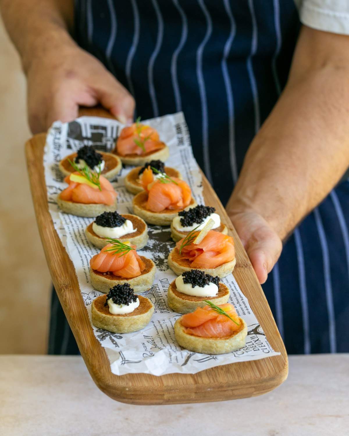 Potato Blinis canapes with various toppings on a wooden board