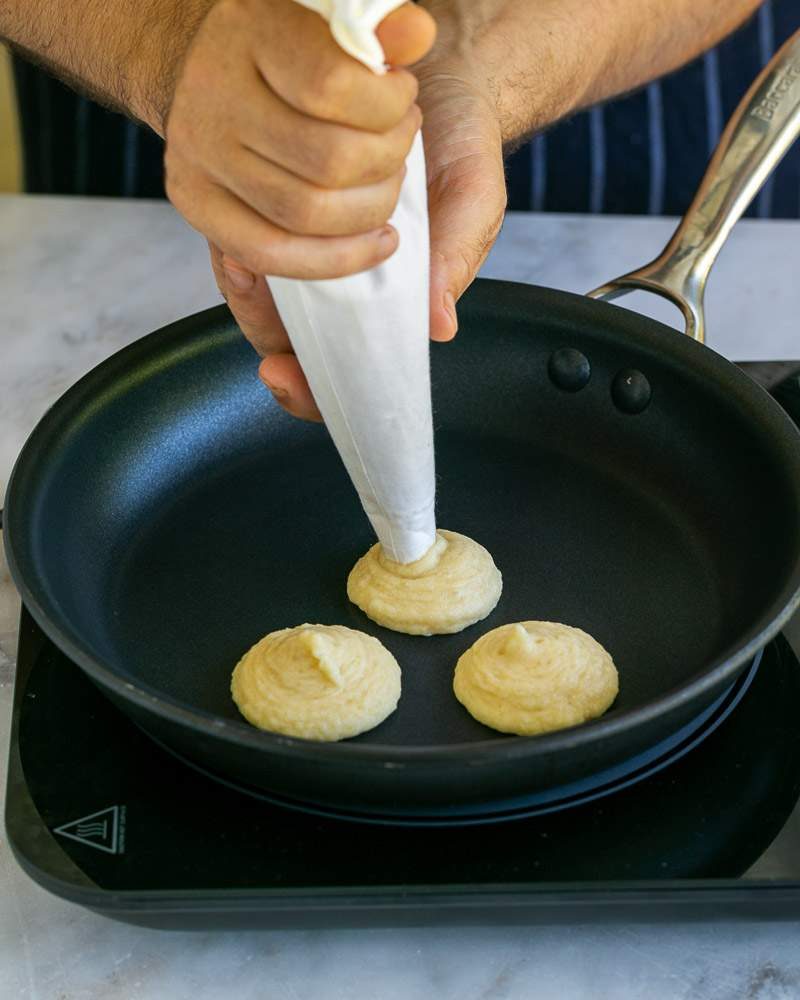 Piping blinis batter in pan