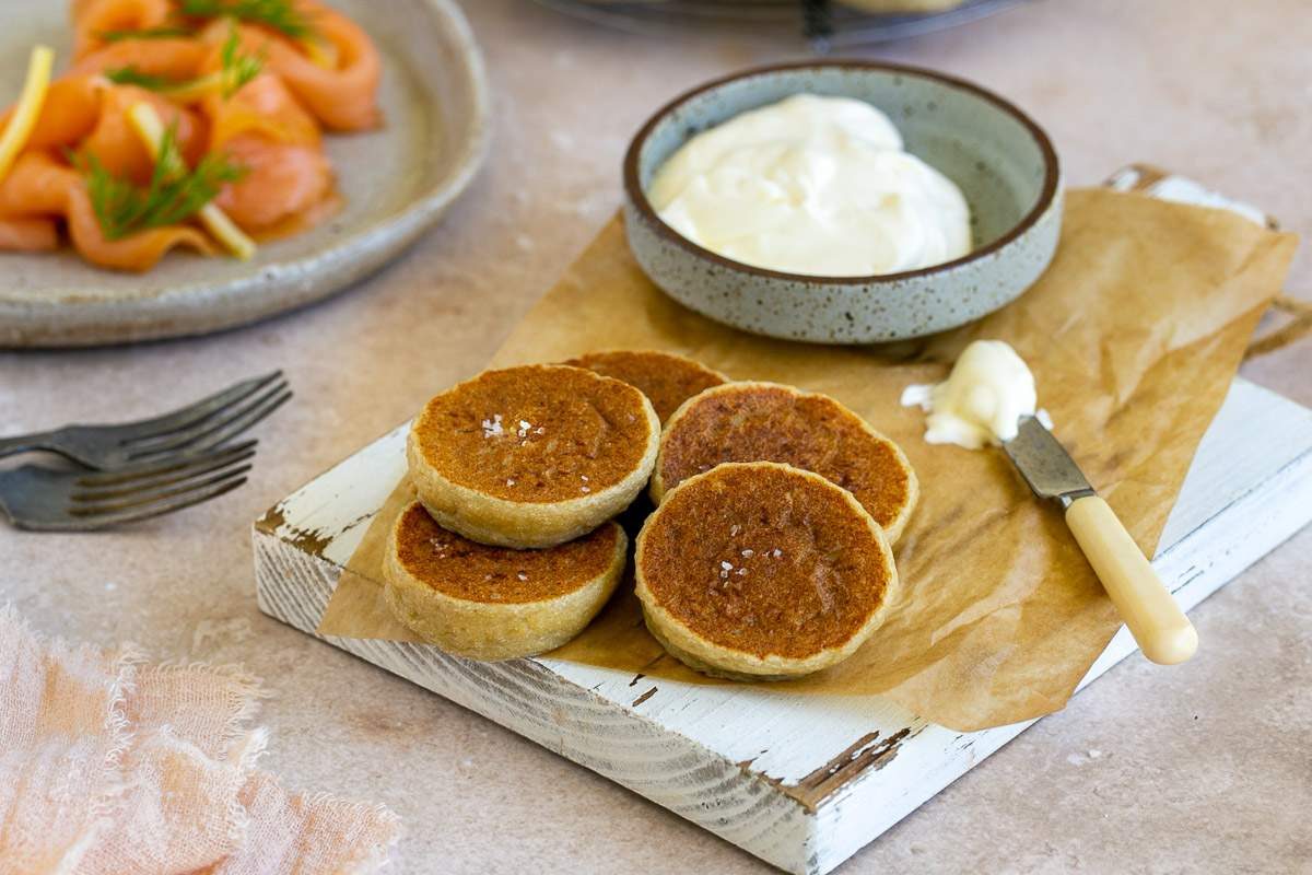 Potato Blinis with creme fraiche on a white wooden board