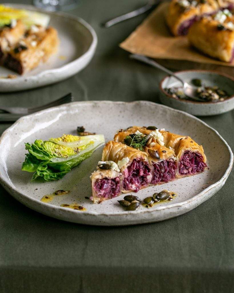Slice of red cabbage pie with feta served with salad