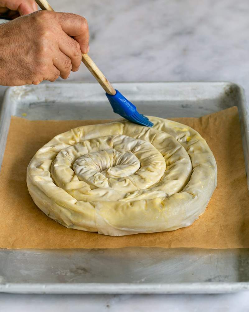 Brushing the rolled spiral pie with melted butter