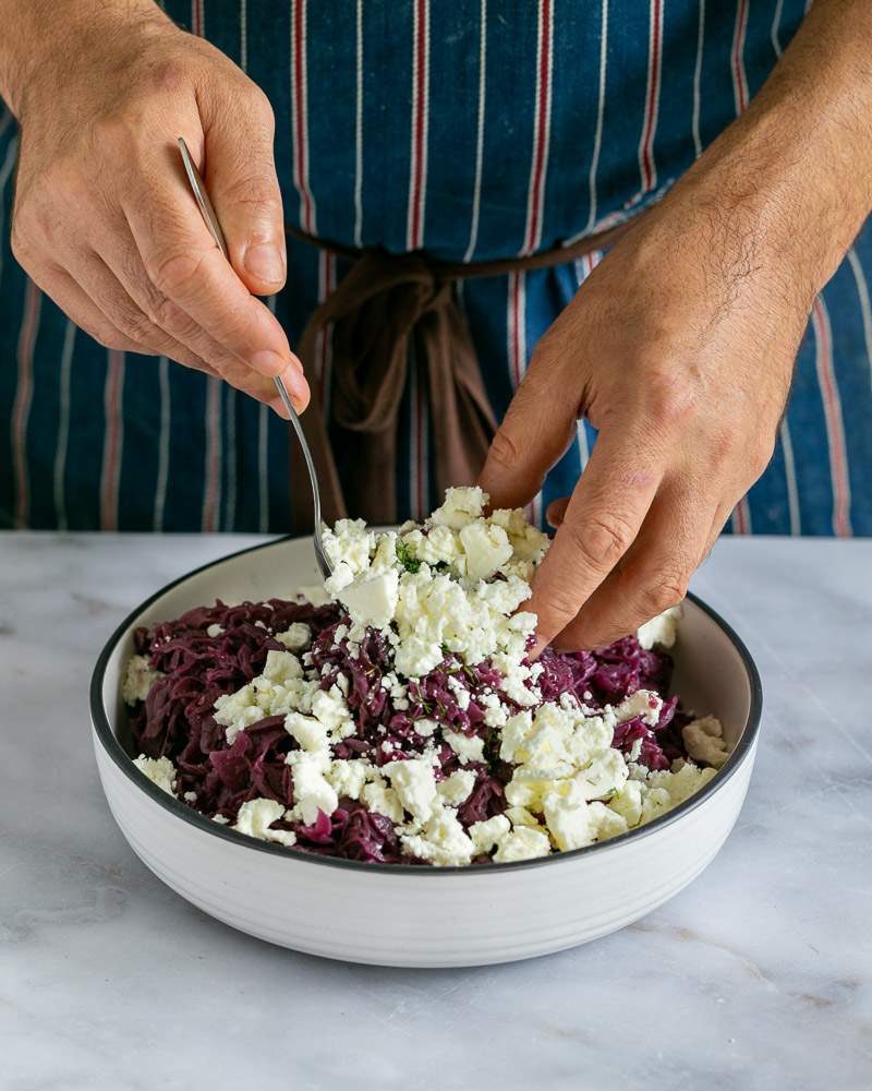 Mixing feta cheese with braised red cabbage