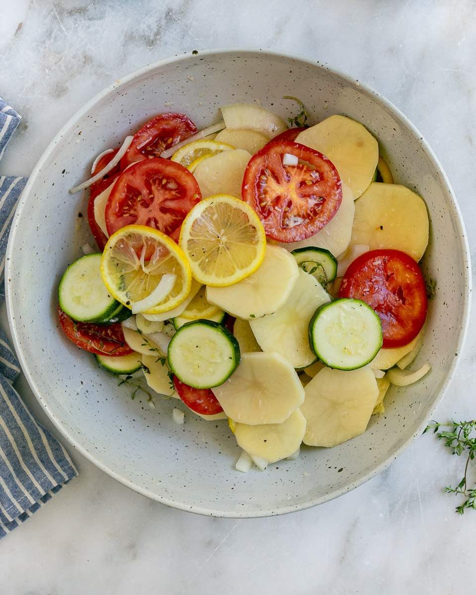 Vegetables mixed with seasoning and herbs in a bowl