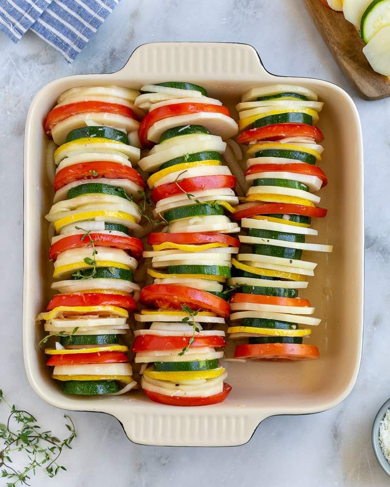 Layered and stacked sliced vegetables in baking dish