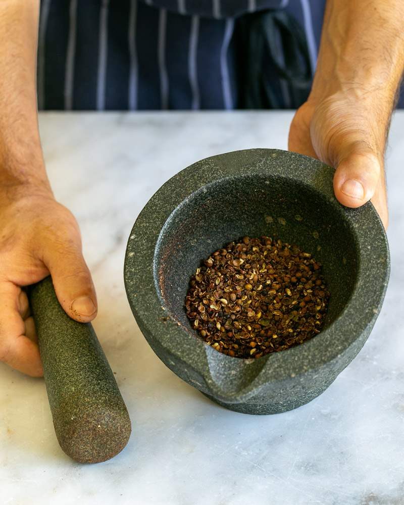 Szechuan peppers crushed in a mortar pestel