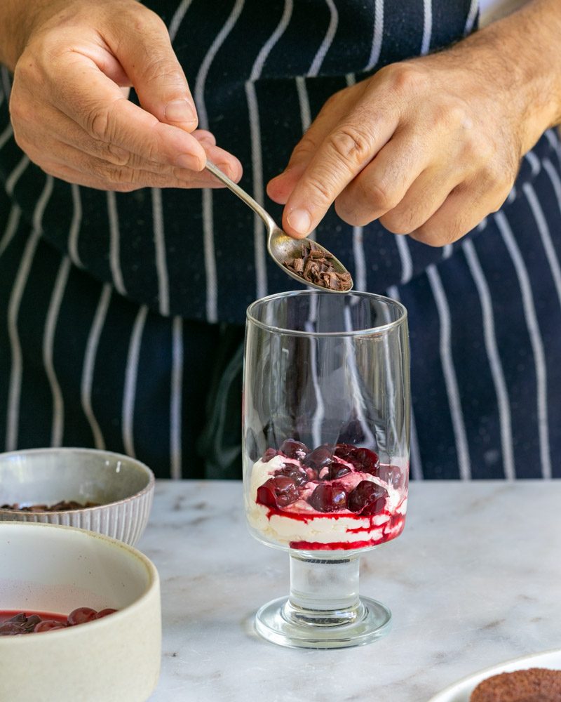 Sprinkling chocolate curls onto the cherry layer