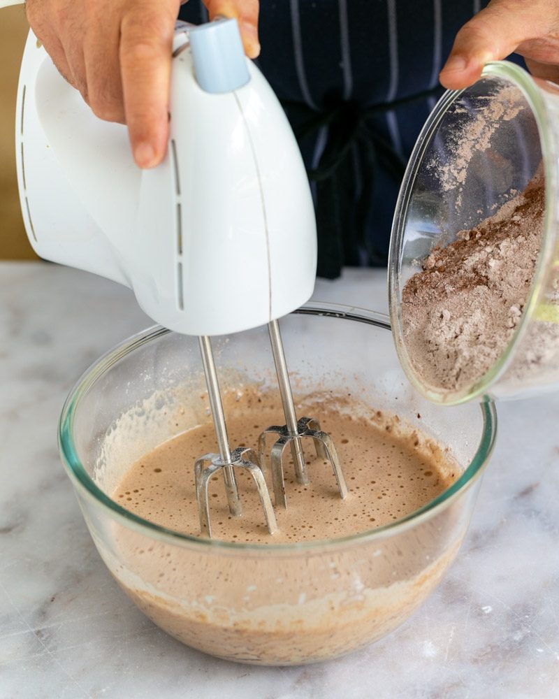 Adding dry ingredients to wet ingredients to make chocolate sponge cake