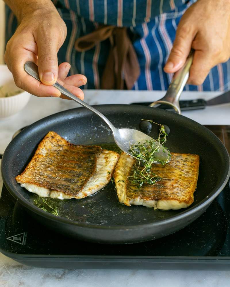 Basting the fish fillet with butter and thyme