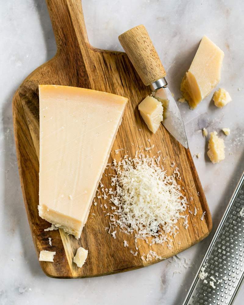 Block of parmesan cheese next to grated cheese