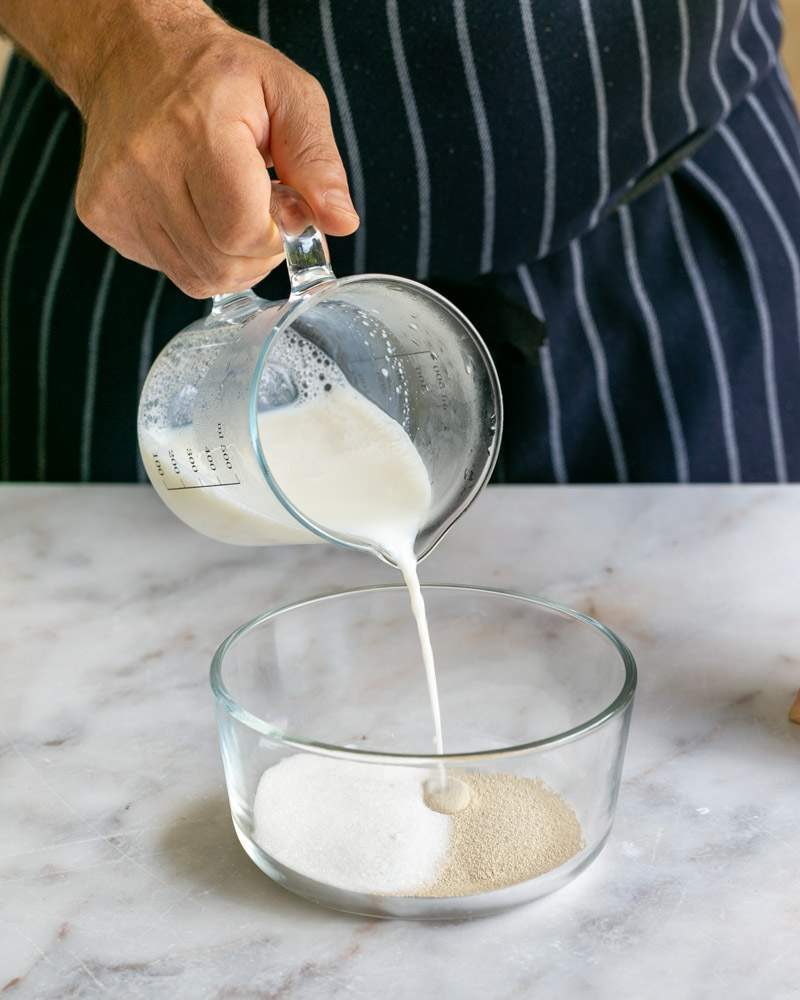 Warm milk added to yeast and sugar in a bowl