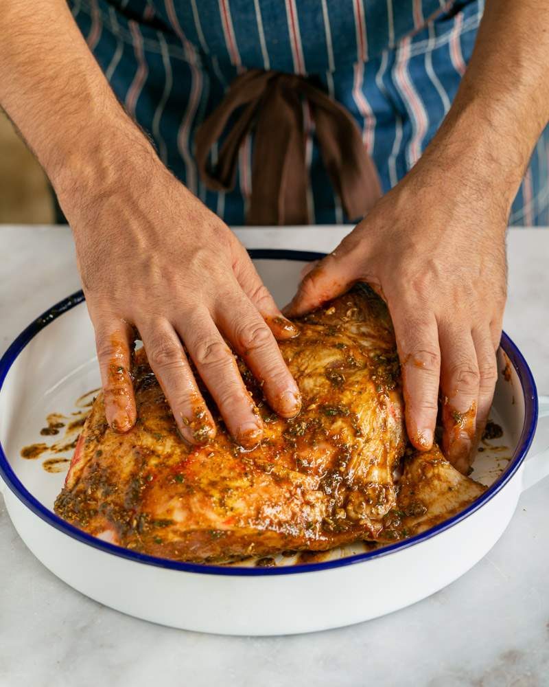 Rubbing marinade into the lamb shoulder with hands