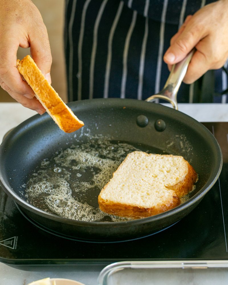 Adding brioche slices to hot pan with butter