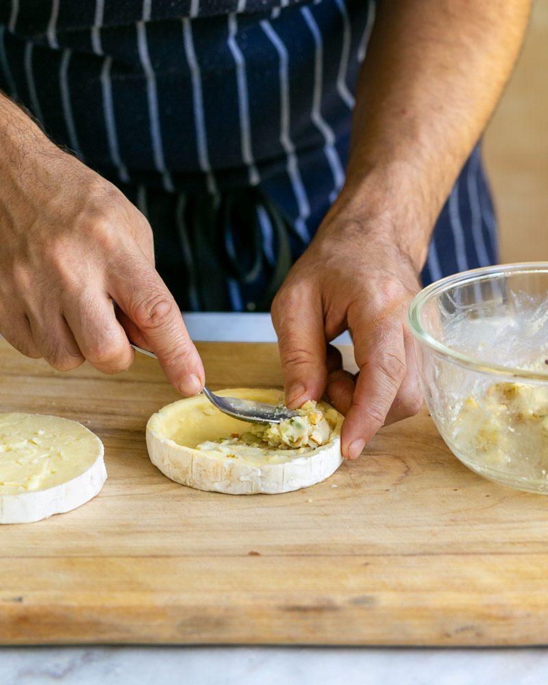 Stuffing cheese and nuts back into the scooped brie