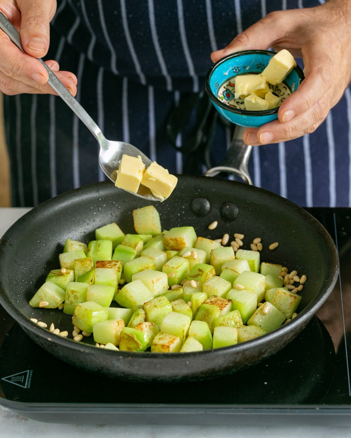 Adding butter to roasted chokos in pan