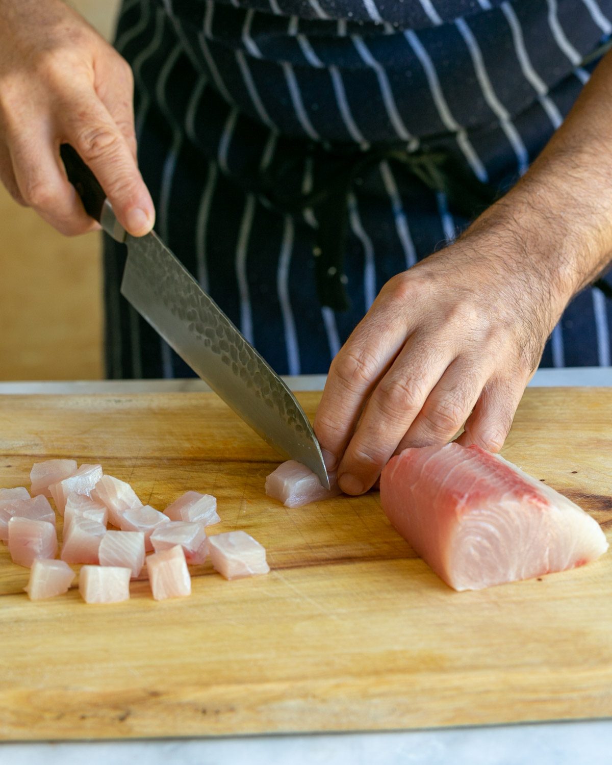 Cutting Hamachi fish into cubes to make crudo