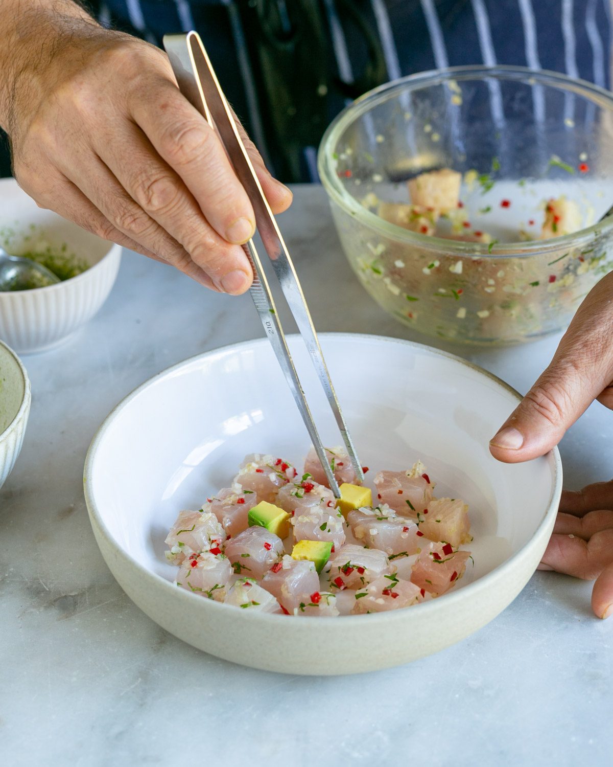 Adding the avocado cubes in between hamachi cubes