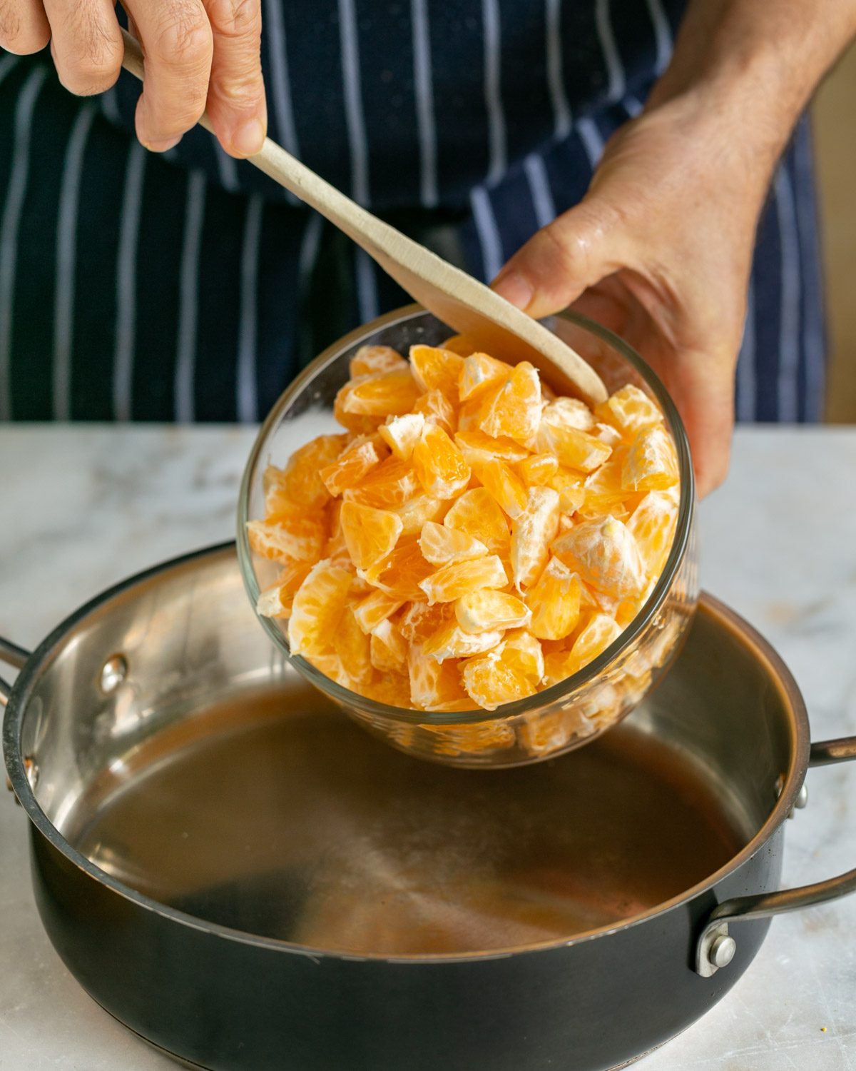 Cut mandarin added to wide pot to cook