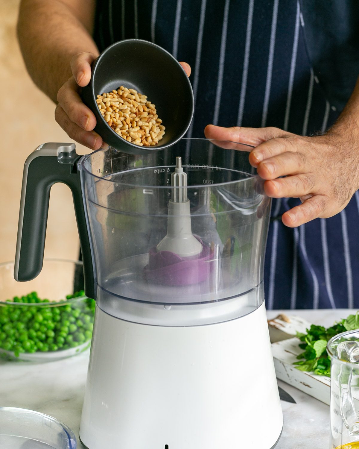 Adding roasted pine nut seeds to food processor