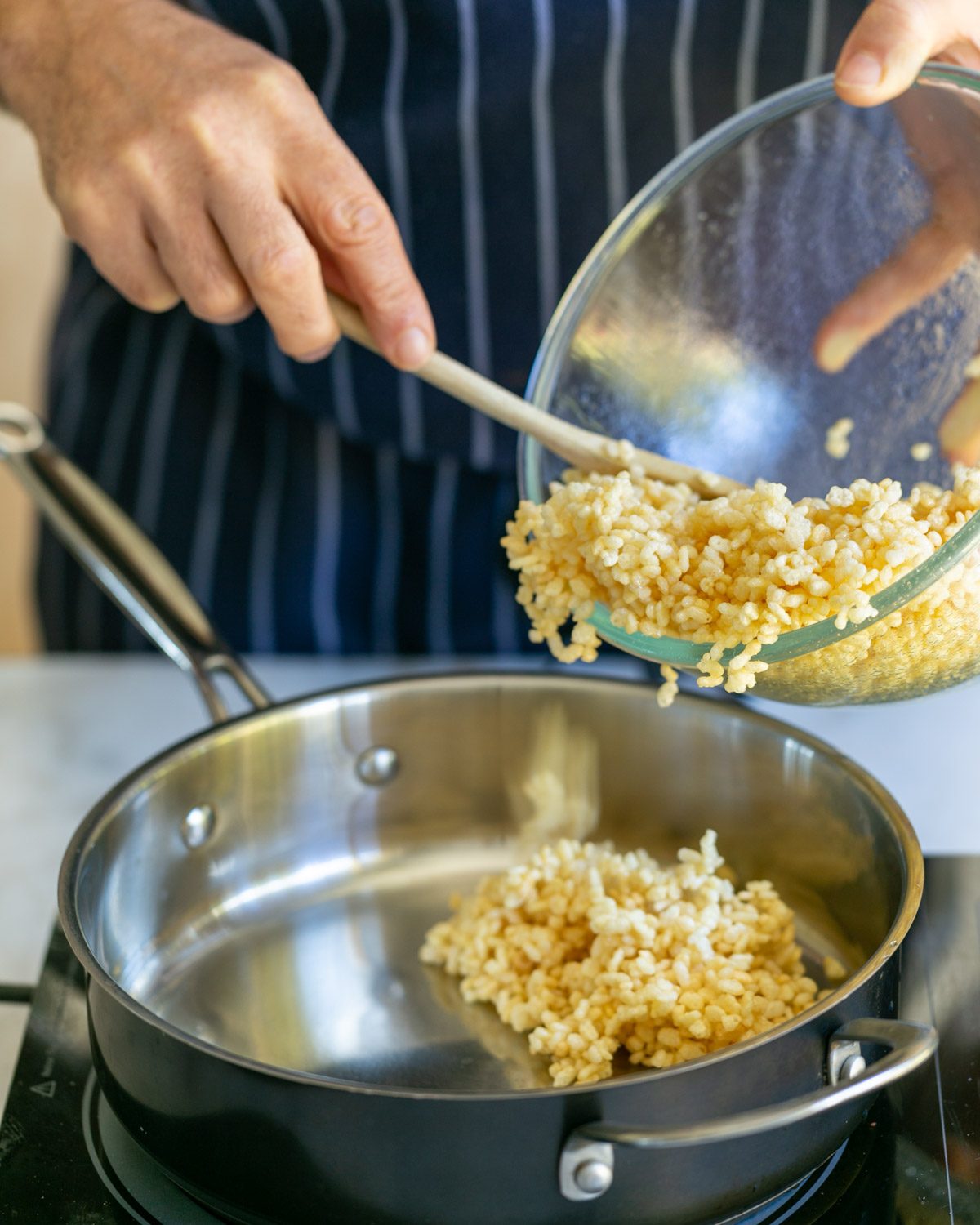 Adding puffed rice with sugar syrup to a pan