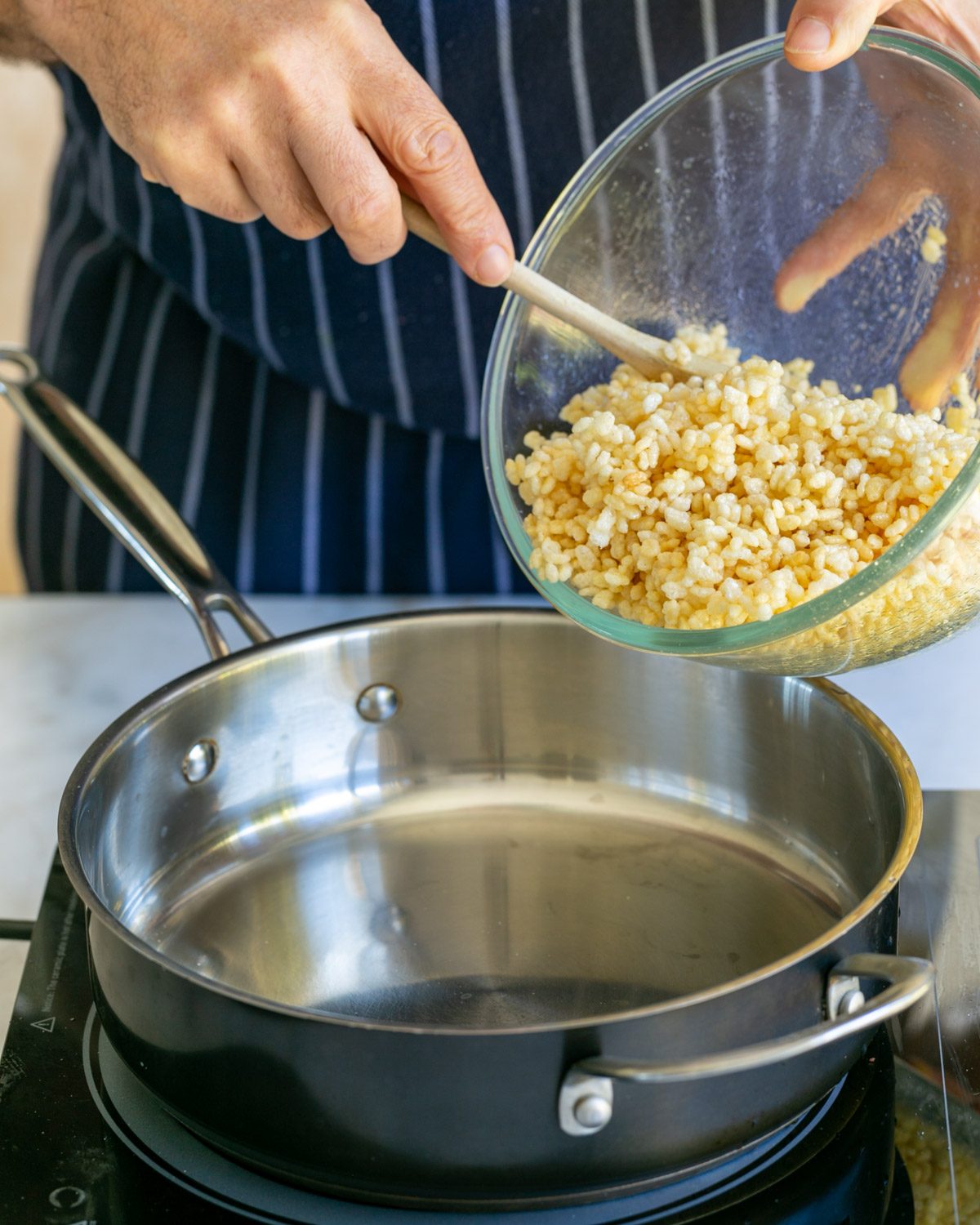 Adding puffed rice with sugar syrup to a pan