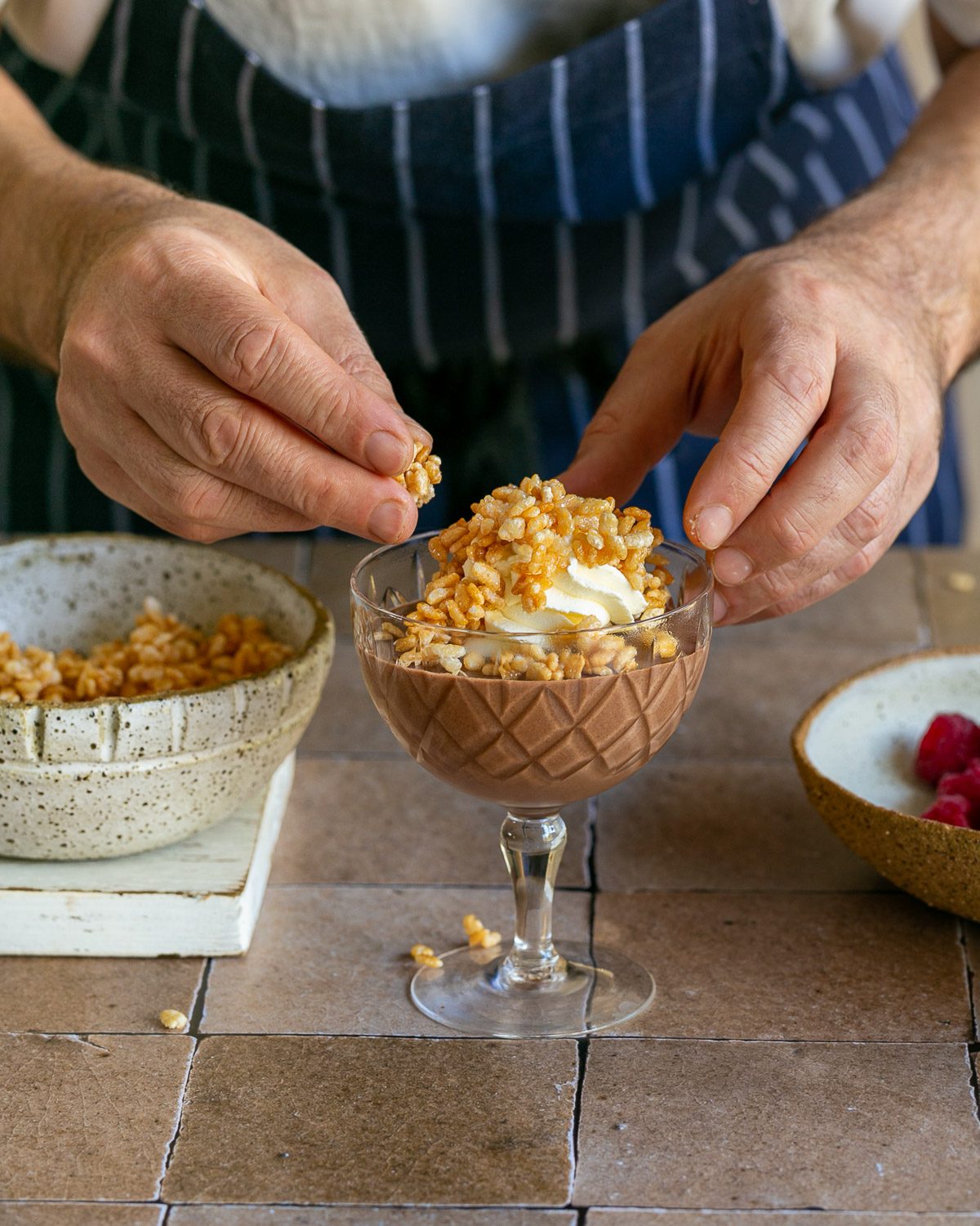 decorating dessert with whipped cream and caramelised puffed rice