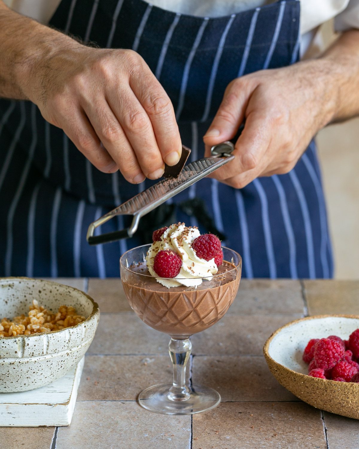 Decorating dessert with whipped cream raspberries and dark chocolate