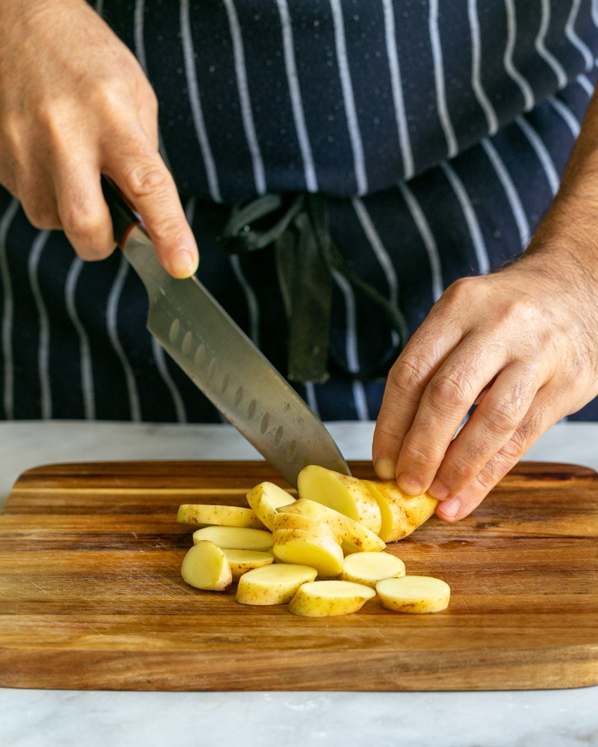 Cutting Kipfler potatoes on a chopping board