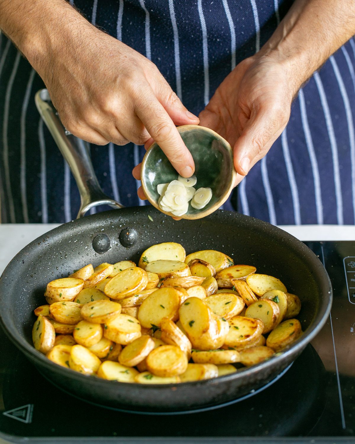 Adding sliced garlic to the potatoes