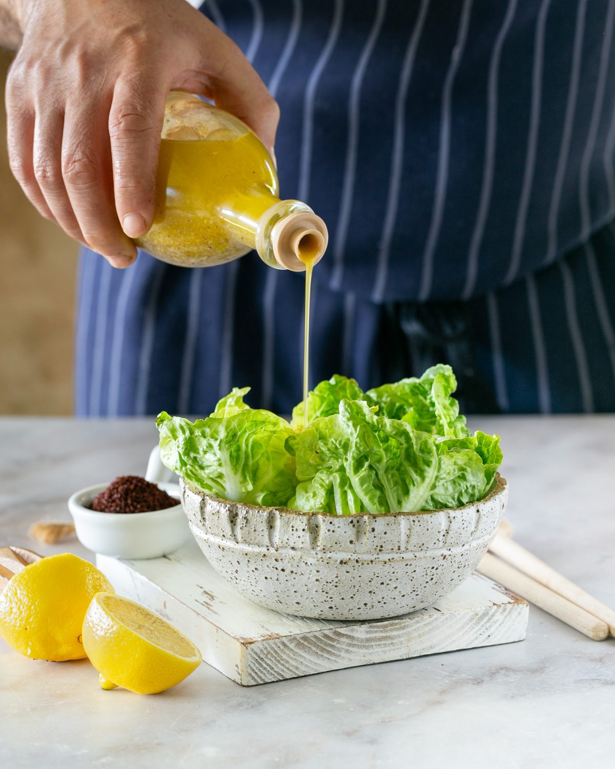 Pouring the sumac dressing over salad leaves