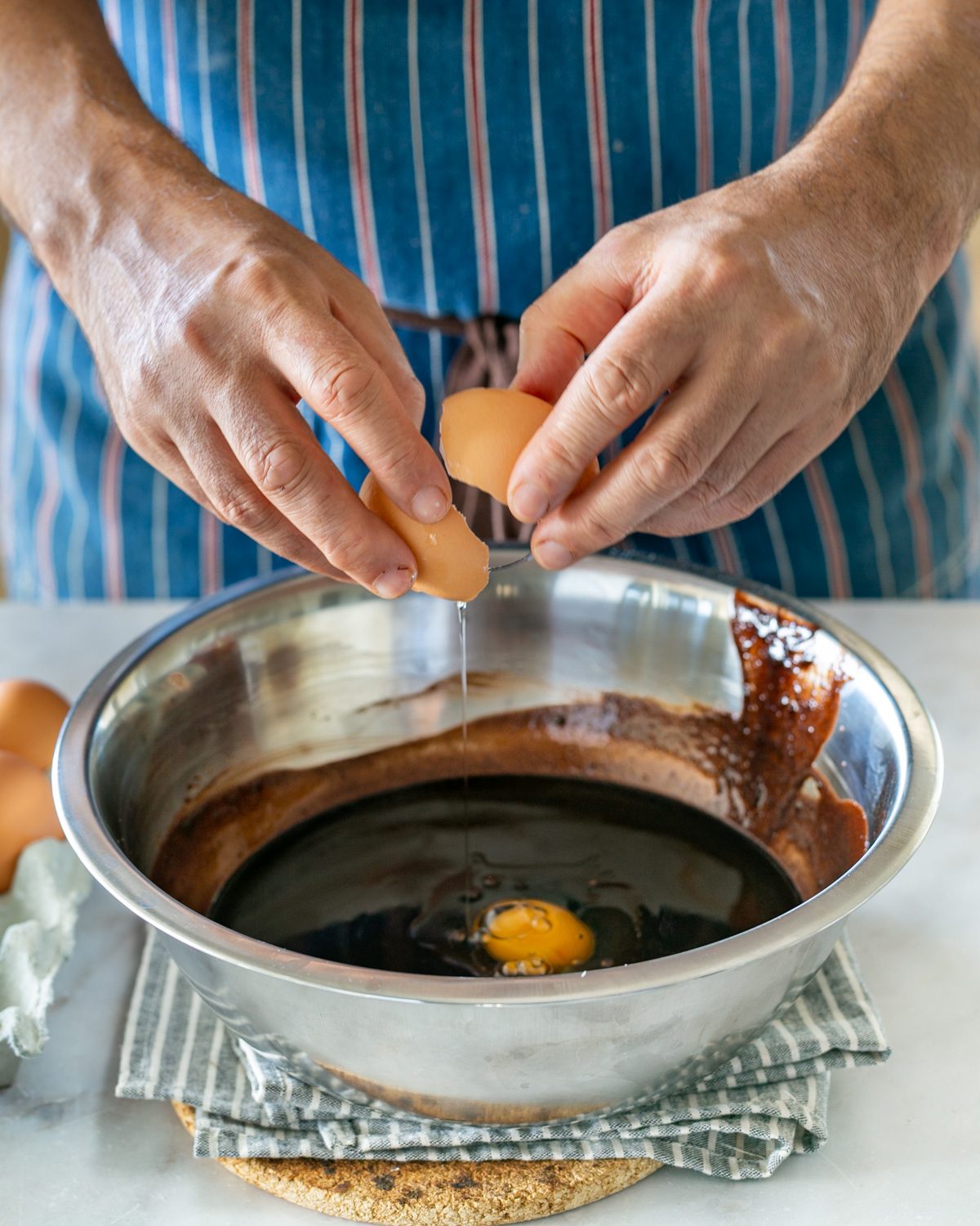 adding eggs to melted chocolate to make walnut brownie